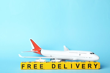 Toy plane and cubes with words FREE DELIVERY on light blue background, space for text. Logistics...