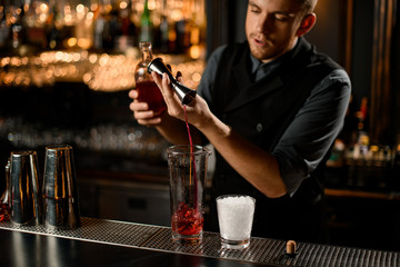 Bartender pouring liquor from jigger to glass