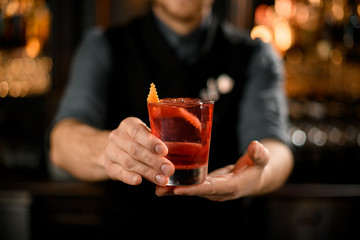 Bartender holding alcohol drink with orange peel