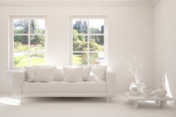 Fototapeta premium Mock up of stylish room in white color with sofa and green landscape in window. Scandinavian interior design. 3D illustration