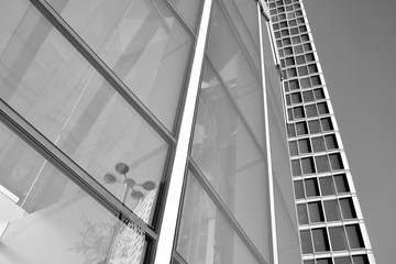 Obraz premium Sun rays light effects on urban buildings in sunset. Modern office building detail, glass surface with sunlight. Business background. Black and white.