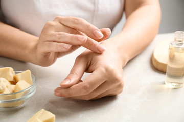 Woman applying organic cocoa butter at table, closeup