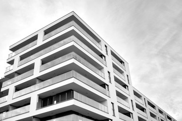 Fototapeta premium Sun rays light effects on urban buildings. Fragment of modern residential apartment with flat buildings exterior. Detail of new luxury house and home complex. Black and white.