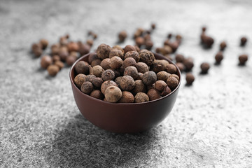 Black peppercorns in bowl on grey table
