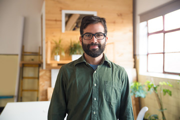 Positive hipster entrepreneur, IT expert, software developer posing in modern office. Bearded young...