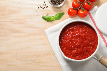 Flat lay composition with delicious tomato sauce on wooden table, space for text