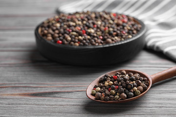 Different peppercorns on light grey wooden table, closeup
