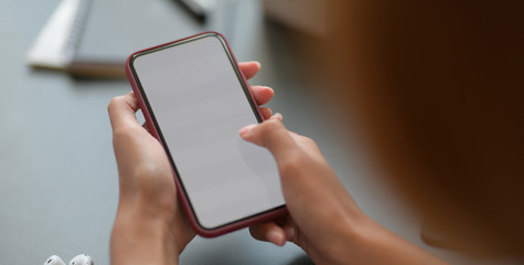 Cropped shot young businesswoman holding blank screen smartphone while working