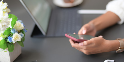 Cropped shot of young businesswoman working on her project while using smartphone in modern workplace