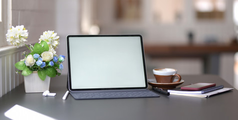 Close-up view of dark stylish workplace with blank screen digital tablet and office supplies on black table