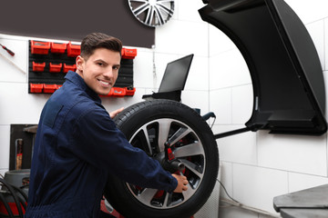 Fototapeta na wymiar Man working with wheel balancing machine at tire service