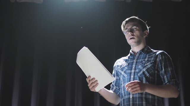 Medium shot of actors and actresses rehearsing a scene in a theater. Medium shot of an actor performing a monologue in a theater while holding his script