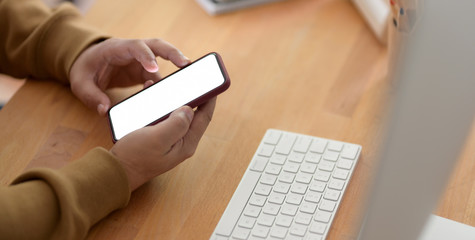 Close-up view of young man using smartphone while working on the project