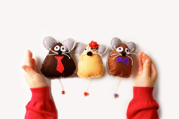 Sewing mouse toys from felt on children's hands.