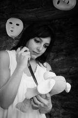 mentally confused woman with cuddly bear and scissor in front of a wall