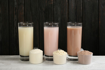 Protein shakes and powder on white wooden table