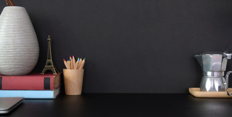 Close-up view of dark modern office room with decorations and copy space on black table and black wall