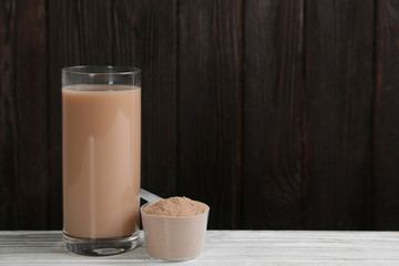 Protein shake and powder on white wooden table, space for text
