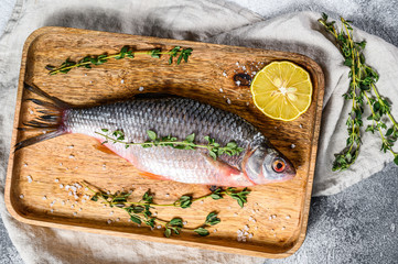 crucian carp on a wooden tray. River organic fish. Gray background. Top view