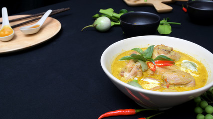 Cropped shot of chicken green curry and ingredients on black desk background