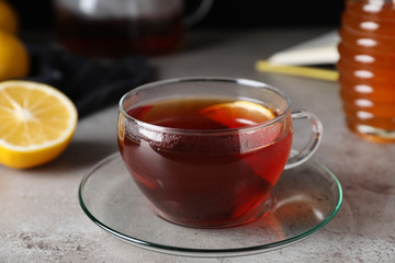 Fresh tea with honey and lemon on light grey table, closeup