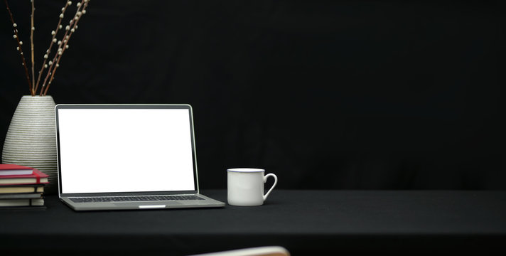 Cropped shot of dark trendy workplace with laptop computer and office supplies with copy space