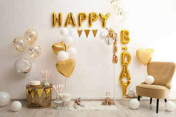 Phrase HAPPY BIRTHDAY made of golden balloon letters in decorated room