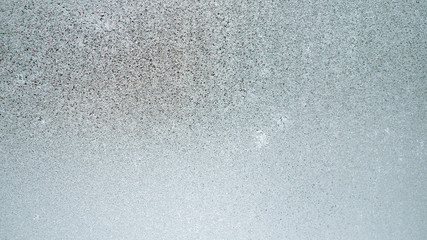 Ice and frost on a window pane in winter. Weather forecast: cold, frost, cooling. Abstract background or wallpaper of a greenish or bluish tint. Harsh season