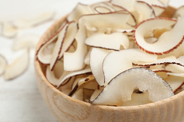 Tasty coconut chips in wooden bowl, closeup