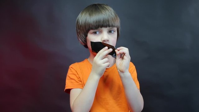 Imitation of child abuse, a child with a black ribbon on his lips.