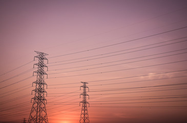 High voltage electric tower line silhouette at sunset.