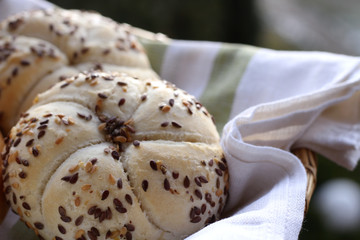 Tasty freshly baked butter kaiser roll with linseed and sunflower seeds. Pastrys in basket. Blurred background. Concept of fresh pastry.