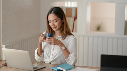 Portrait of beautiful asian businesswoman working on her project and drinking a coffee