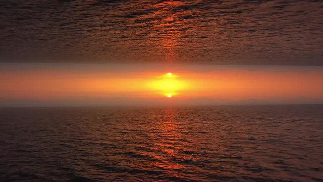 Aerial view on surreal upside down mirrored world, orange sun and sea on background