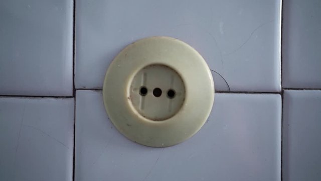 Old socket on the wall. Short circuit. Old power grid. Voltage drop in the room. The light is blinking. Danger. Lighting turn on and off. Power source. House of Horror.