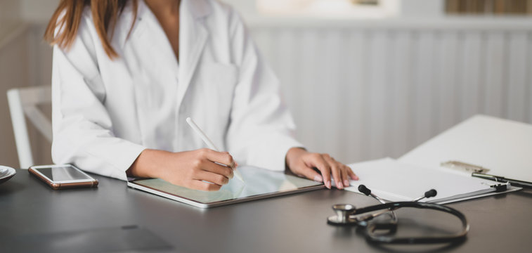 Cropped shot of young female doctor working on medical charts and document in her office