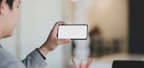 Cropped shot of young businessman looking at blank screen smartphone