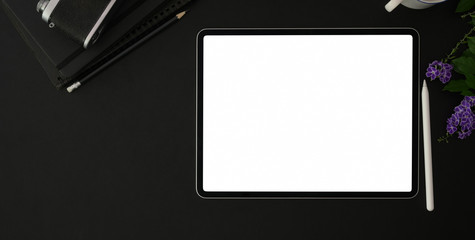 Top view of trendy photographer workplace with blank screen tablet and office supplies on black table