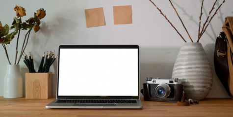 Cropped shot of photographer office room with blank screen laptop computer, office supplies and camera