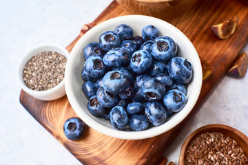 selected blueberries in a ceramic bowl on a wooden cutting board, top view