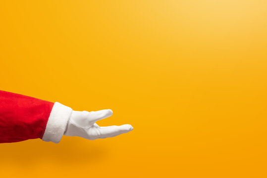 Santa Claus Hand On Yellow Or Orange Isolated Background.