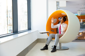 Focused businessman using VR headset. Full length view of young African American businessman...