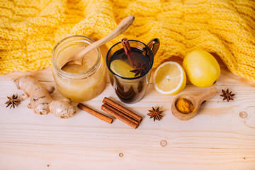 Cup warm water with lemon, honey, ginger root, cinnamon and anise. Ingredients on a wooden background. Concept of alternative medicine.