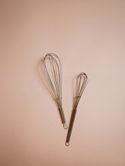 two whisks on pastel background