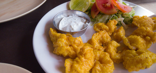 Breaded shrimp with white sauce with vegetables on a white plate