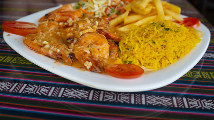 Fried breaded shrimp with rice and vegetables on a white plate