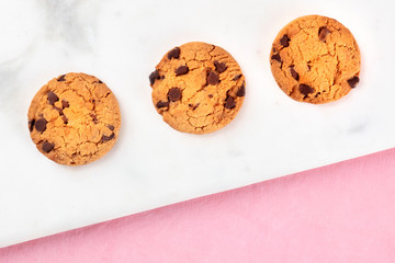 Chocolate chip cookies, gluten free, shot from the top on a white marble and pink background with copy space