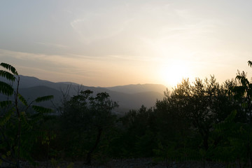 Fototapeta na wymiar Sun setting behind a green hill
