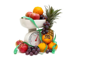 kitchen scales, fruits and measuring tape on a white background
