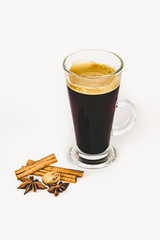 GLASS CUP OF COFFEE WITH CINNAMON ON WHITE BACKGROUND